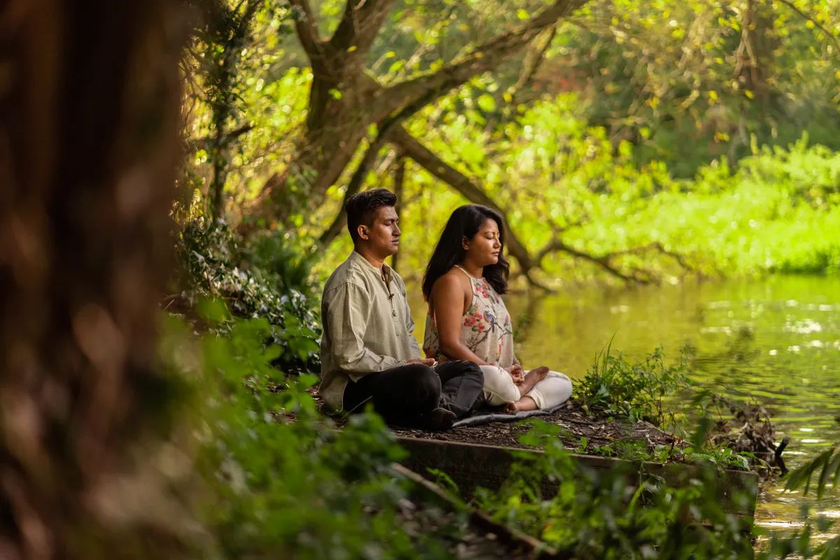 A couple sitting peacefully by a calm river
